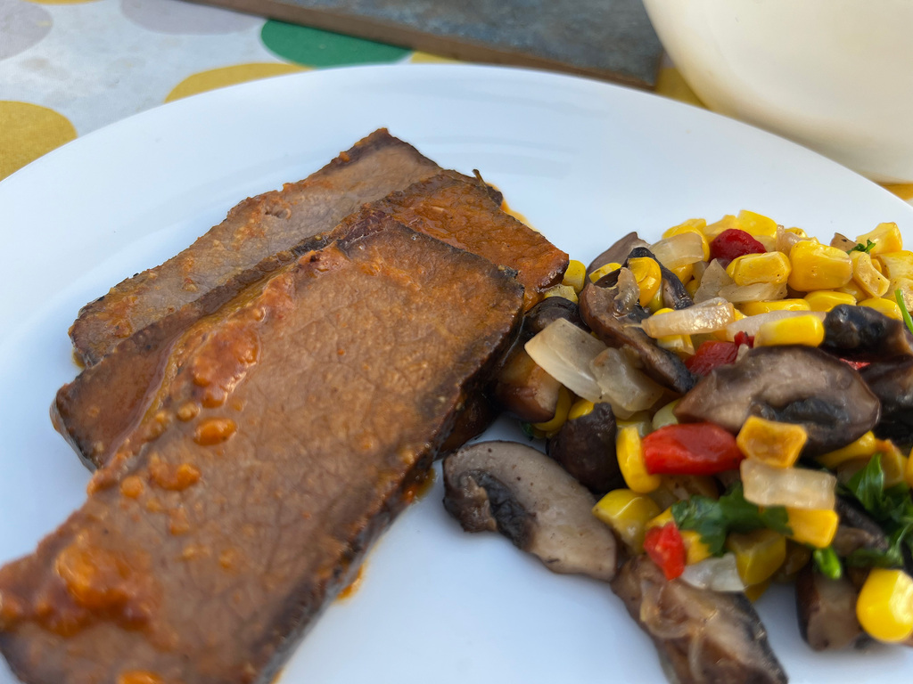 sliced brisket served with a corn, mushroom salad